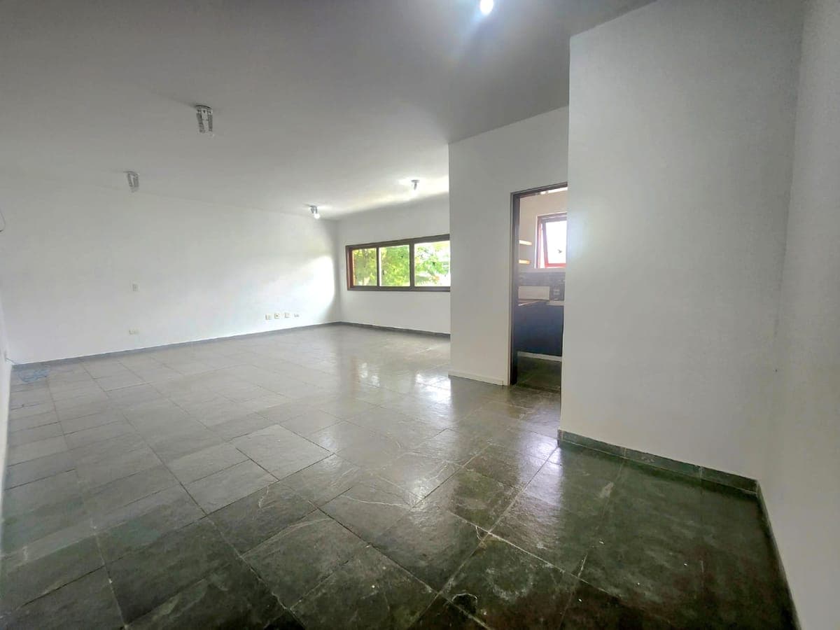Sala comercial ampla com piso de pedra e janela para o jardim